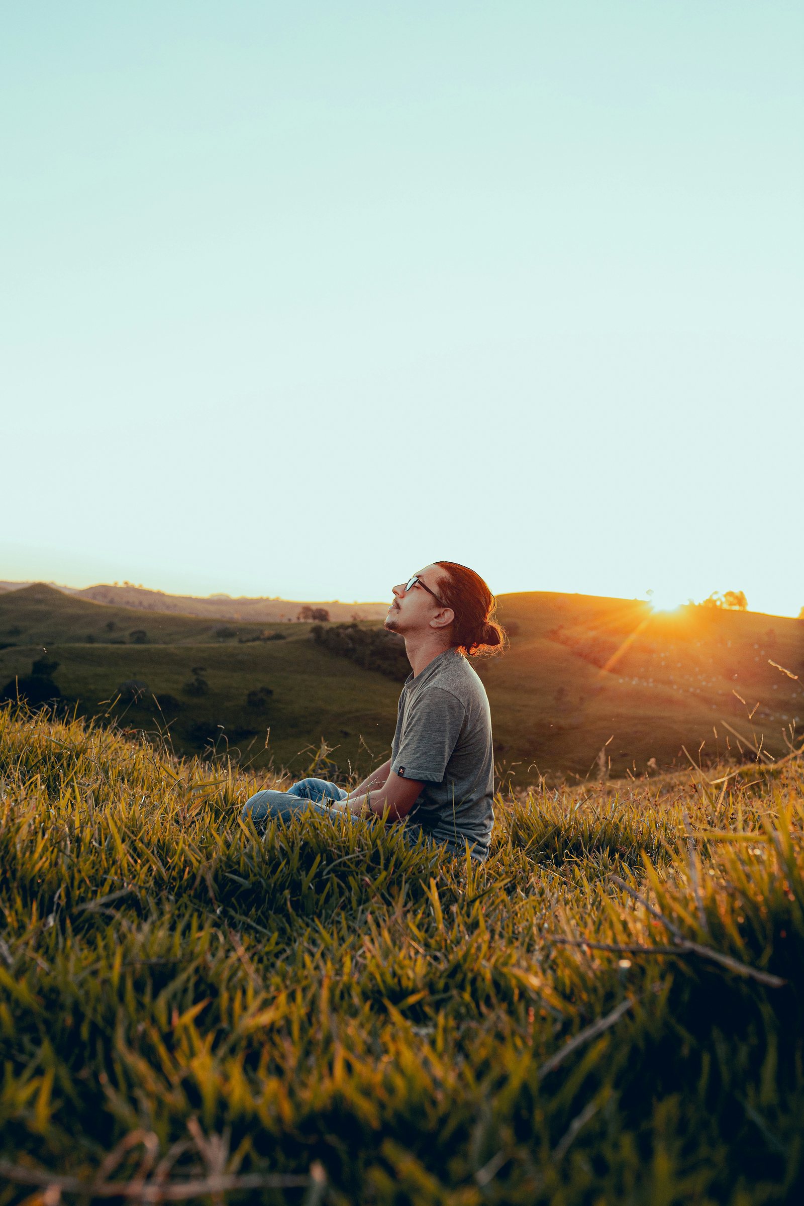 A person sitting quietly on a hillside, facing the sunset